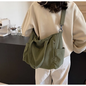 Detail of green corduroy tote bag featuring adjustable strap and side pocket on a person