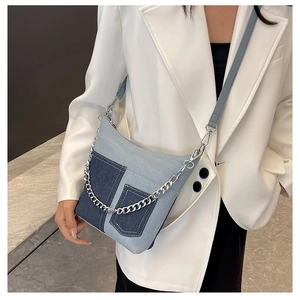 Chic patchwork denim bucket bag with silver chain strap shown on a model in white blazer