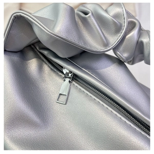 Detail of silver baguette bag with metallic pleated handle and metal zipper closure