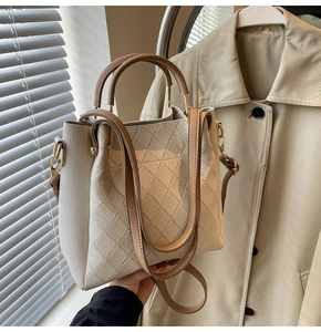 Detail showing the quilted rhombus pattern and leather handle of a chic bucket bag