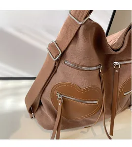Detail view of brown canvas bag featuring heart-shaped leather pockets and metallic zippers