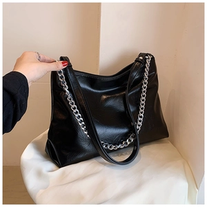 Detail of black soft leather tote bag with thick silver chain and fine pleat texture