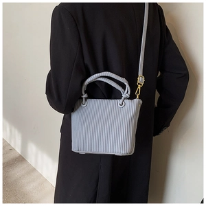 Detailed view of light blue pleated bucket bag with gold hardware and shoulder strap