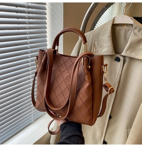 Detail of a brown leather bucket bag with quilted stitching and gold hardware
