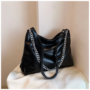 Detail view of large black tote bag with glossy wrinkled leather and silver chain
