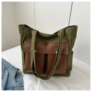 Detail of army green canvas tote bag with brown faux leather pockets and metal magnetic buckles