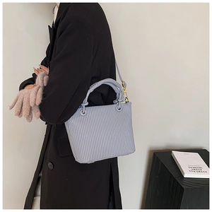 Detailed view of pleated texture on light blue bucket bag with gold hardware