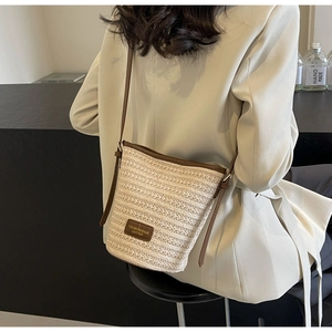 Detailed view of beige woven bucket bag with dark brown leather straps on a model