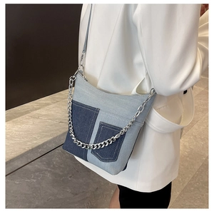 Detail showing two-tone denim crossbody bag with silver chain and stitched pockets