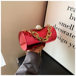 Detail of red metallic cylinder clutch bag with large pearl clasp and gold chain handle