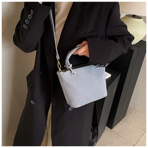 Detail of grey-blue pleated bucket bag featuring woven ring handle and gold hardware