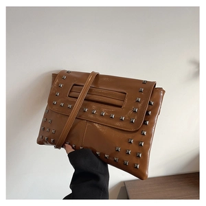 Dettaglio della borsa a busta in pelle PU marrone lucida con borchie metalliche quadrate