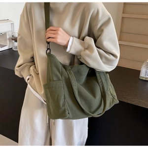 Detail of army green corduroy tote bag showing functional side pockets and wide shoulder strap
