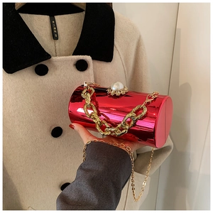 Detail of red cylindrical acrylic clutch bag with large pearl clasp and gold chain strap