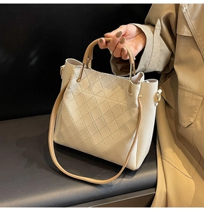 Detail of quilted leather bucket bag with gold hardware and cylindrical handle straps