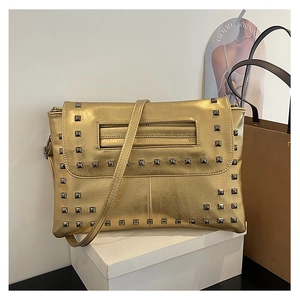 Dettaglio della borsa a busta metallizzata dorata con borchie quadrate grigie e tracolla