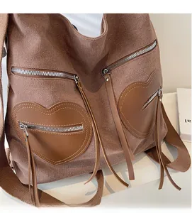 Close-up of brown corduroy backpack featuring heart-shaped leather patches and zippers