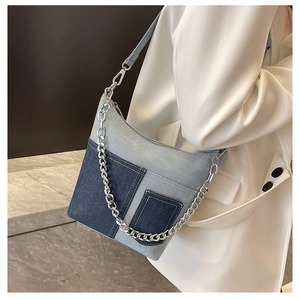 Close-up of patchwork denim shoulder bag with silver chain and decorative pockets