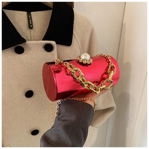 Detail of fuchsia acrylic cylinder clutch with gold chain and large pearl clasp decoration