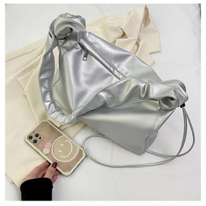 Detail of silver metallic baguette bag with knotted strap and front zipper pocket