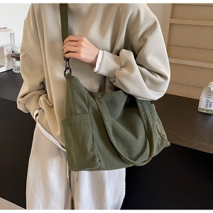 Detail of dark green corduroy tote bag showing thick texture and side pocket for daily use
