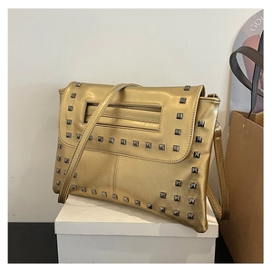 Dettaglio di borsa a tracolla dorata con borchie quadrate argentate e manico rettangolare