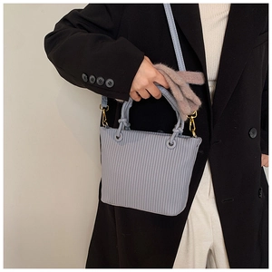 Detailed view of light blue pleated bucket bag with twisted handles and gold hardware accents