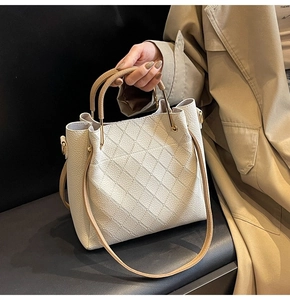Close-up of cream white lychee leather bucket bag with elegant rhombus quilting and gold hardware