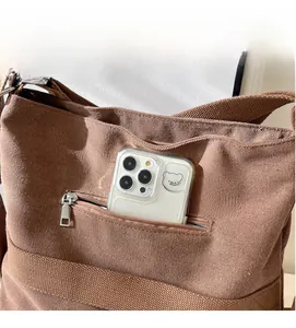 Detail view of large brown corduroy backpack showing outer zipper pocket for smartphone storage
