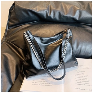 Detail of black faux leather tote bag with silver chain strap and oily texture finish