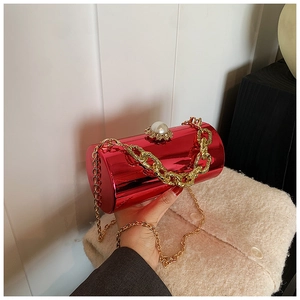 Macro detail of red mirror cylinder bag with gold chain and large pearl clasp