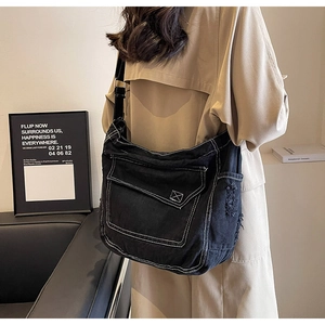 Dettaglio borsa a tracolla in denim nero con cuciture bianche e bordi sfrangiati