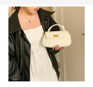 Detail of cream leather handbag showing gold square twist lock and knotted handle texture