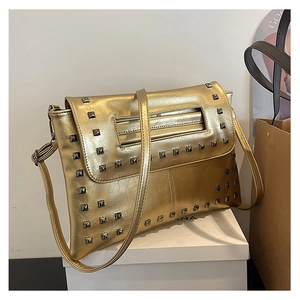 Dettaglio borsa a tracolla in vernice dorata con borchie metalliche quadrate e patta