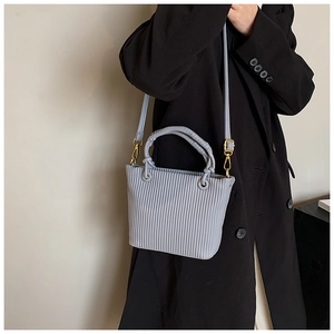 Detailed view of light blue pleated bucket bag with gold hardware and shoulder strap