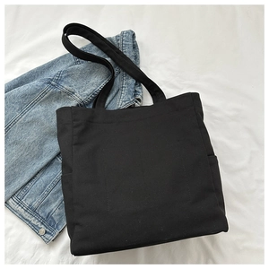 Macro shot of black canvas tote bag showing thick fabric texture and spacious side pockets