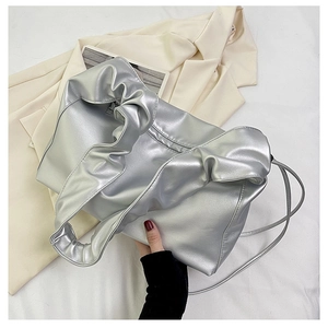 Detail shot of the silver metallic pleated bag featuring a sleek zipper and soft cloud texture