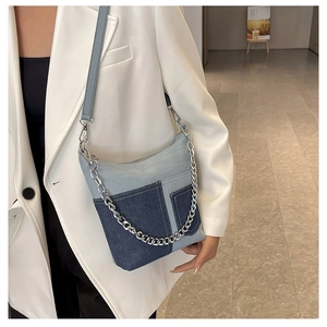 Detail of a denim patchwork crossbody bucket bag featuring silver chain and leather strap