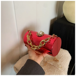 Detail of red acrylic cylinder bag showing pearl clasp and golden chunky chain handle