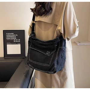 Dettaglio della borsa a tracolla in denim nero con cuciture a contrasto e bordi logori