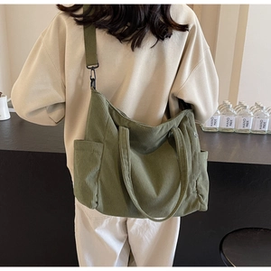 Detailed back view of dark green corduroy tote bag with adjustable wide strap and side pockets