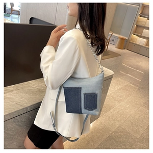 Detail view of denim crossbody bag with silver chain strap and modern curved design