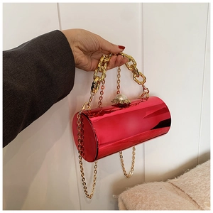 Detail of red cylindrical evening bag featuring golden chain and pearl clasp decoration