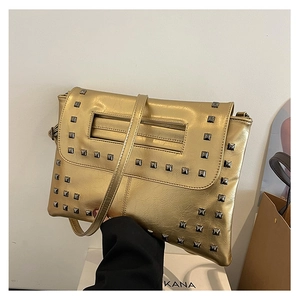 Dettaglio della borsa a mano in ecopelle dorata con borchie quadrate e tracolla