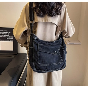 Dettaglio di una grande borsa a tracolla in denim nero con cuciture a contrasto su modella