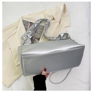 Detail of silver metallic baguette bag showing pleated cloud handle and shiny leather texture