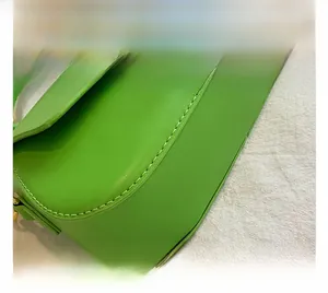 Close-up of bright green leather handbag featuring precise stitching on a woven fabric base