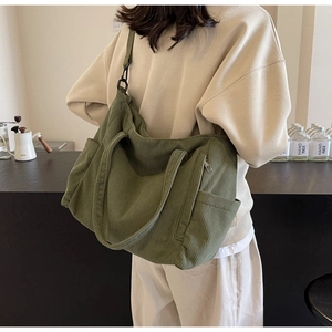 Detail view of deep green corduroy tote bag with side pocket and adjustable strap
