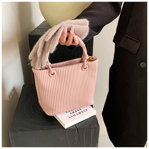 Detailed view of pink pleated bucket bag with gold metal rings and luxury texture