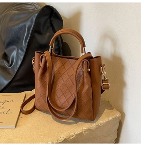 Detail showing the lychee grain texture and rhombus quilted stitching on caramel bucket bag